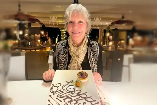 Becca Williams smiling at a restaurant dinner table behind a birthday dessert plate celebrating pure emotional liberation